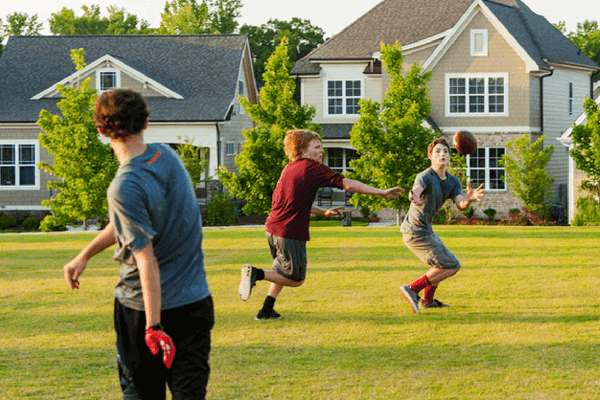 kids tossing a football at park