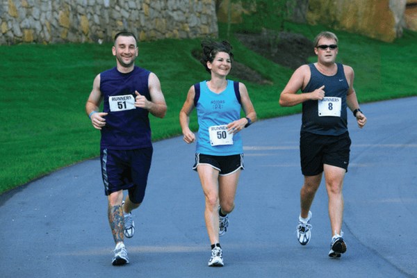 Young adults running along paved trail