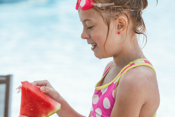 Girl enjoying watermelon by the pool