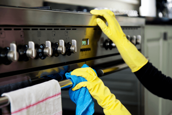 person cleaning an oven appliance